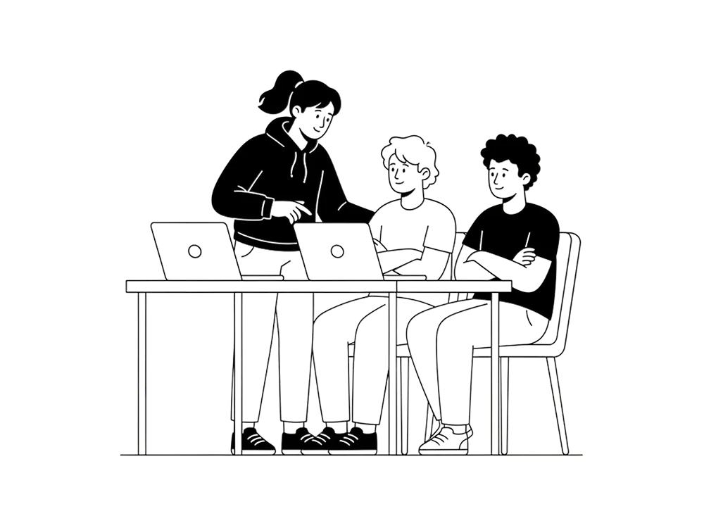 A coach working alongside two engineers at their laptops