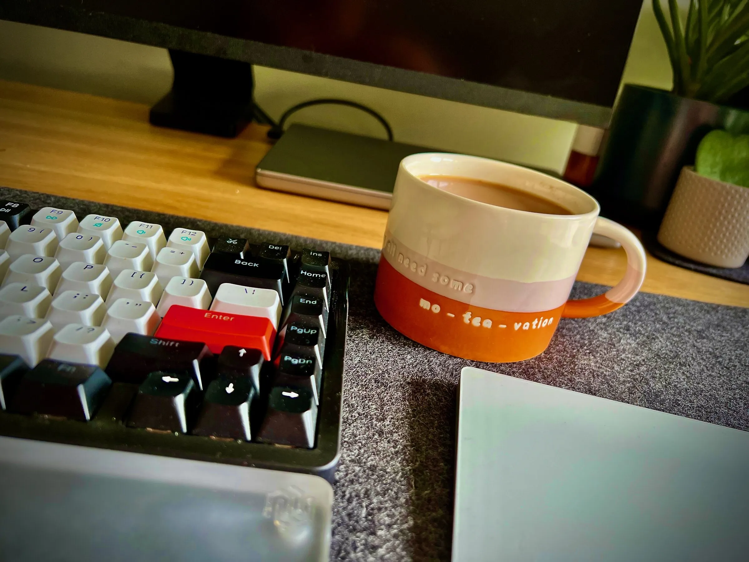 A desk mid-experiment: mechanical keyboard, laptop, and a mug of tea